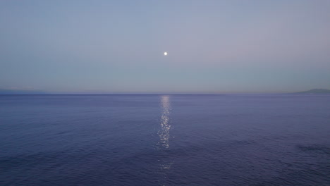 the sea with the reflection of the moon on the water, captured at the break of dawn