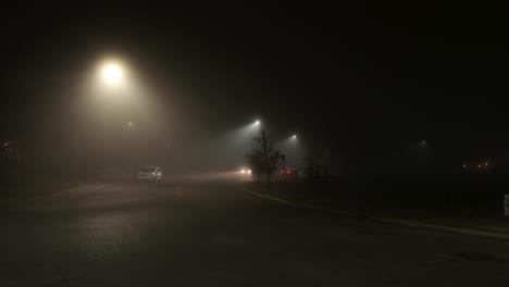 lights illuminate sparse night traffic on secluded foggy city street