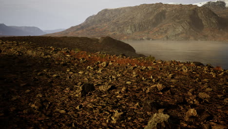 Clear-river-with-rocks-leads-towards-mountains-lit-by-sunset