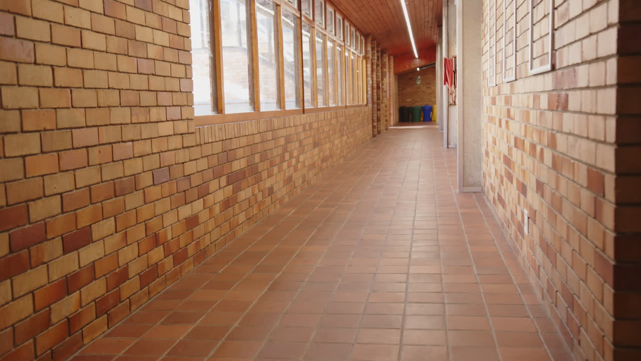 Empty school hallway with brick walls and windows, leading to classrooms, copy space