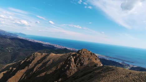 stunning aerial footage from mount praglia with a sweeping view over rocky ridges, the ligurian coastline, and the mediterranean sea. dutch angle and centered forward-facing framing