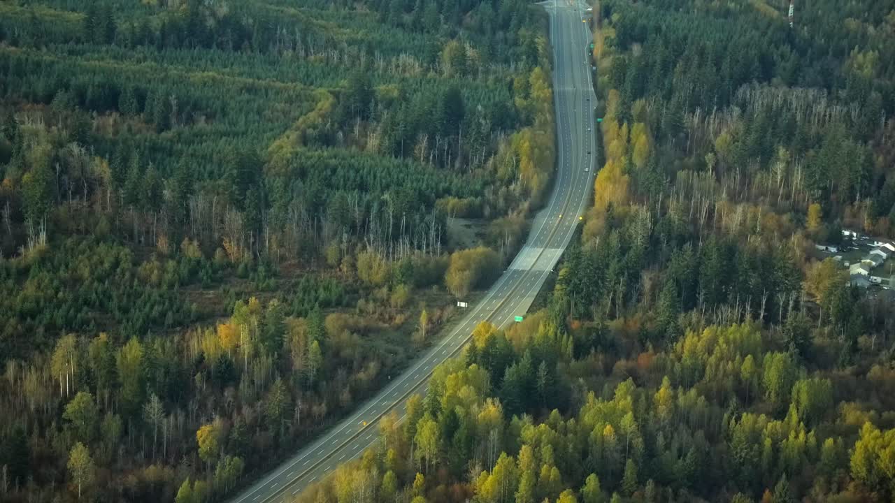 vista aérea de una carretera casi vacía en un paisaje densamente boscoso