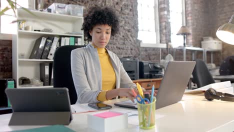 Happy-biracial-casual-businesswoman-using-smartphone-in-office-in-slow-motion