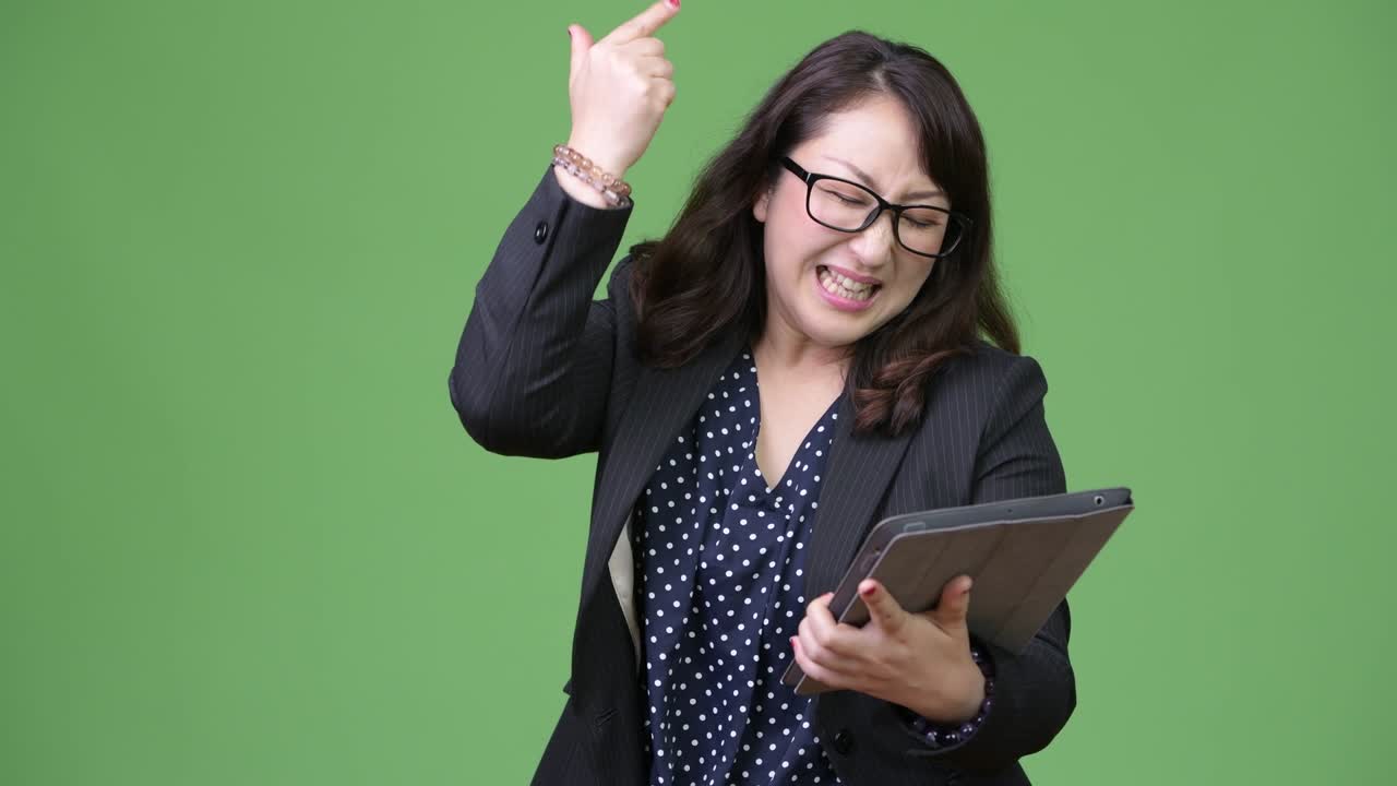 Mature beautiful Asian businesswoman using digital tablet and getting bad news