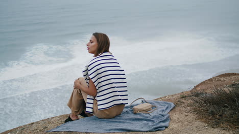 woman resting ocean cliff mountain alone. serene person enjoying ocean landscape