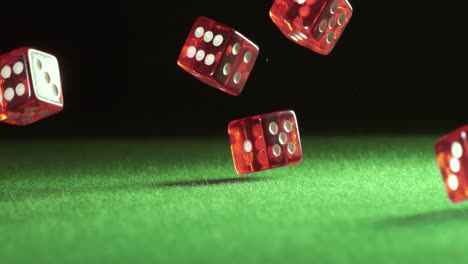 red dice falling and bouncing on green table on a dark background. shot on super slow motion camera 1000 fps.