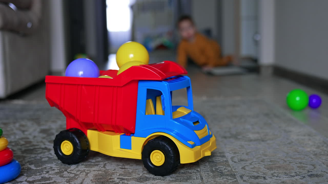 Toddler playing with toy dump truck and balls