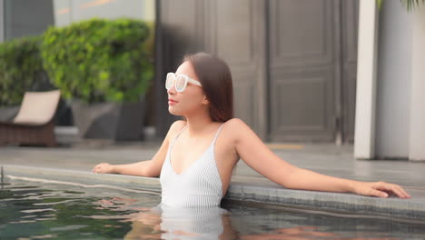 Close-up-of-an-attractive-young-woman-arms-stretched-out-along-the-side-of-a-resort-swimming-pool
