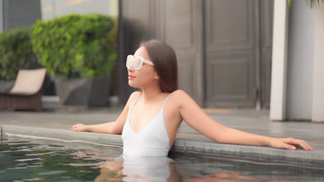 close-up of an attractive young woman arms stretched out along the side of a resort swimming pool