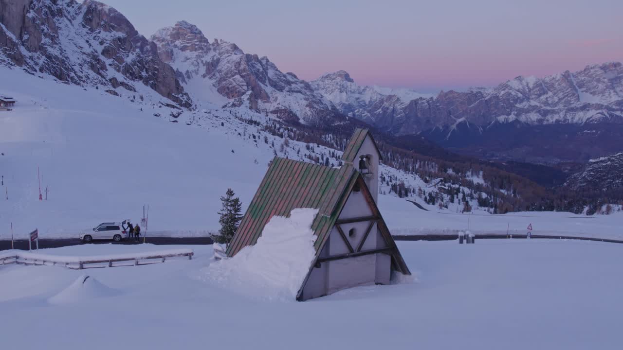 Luftaufnahme von schneebedeckten Gipfeln, Kirche und Straße in der Dämmerung, Passo di Giau, Belluno