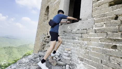 using rocks for support, a man ascends to a window of a watchtower on the great wall of china