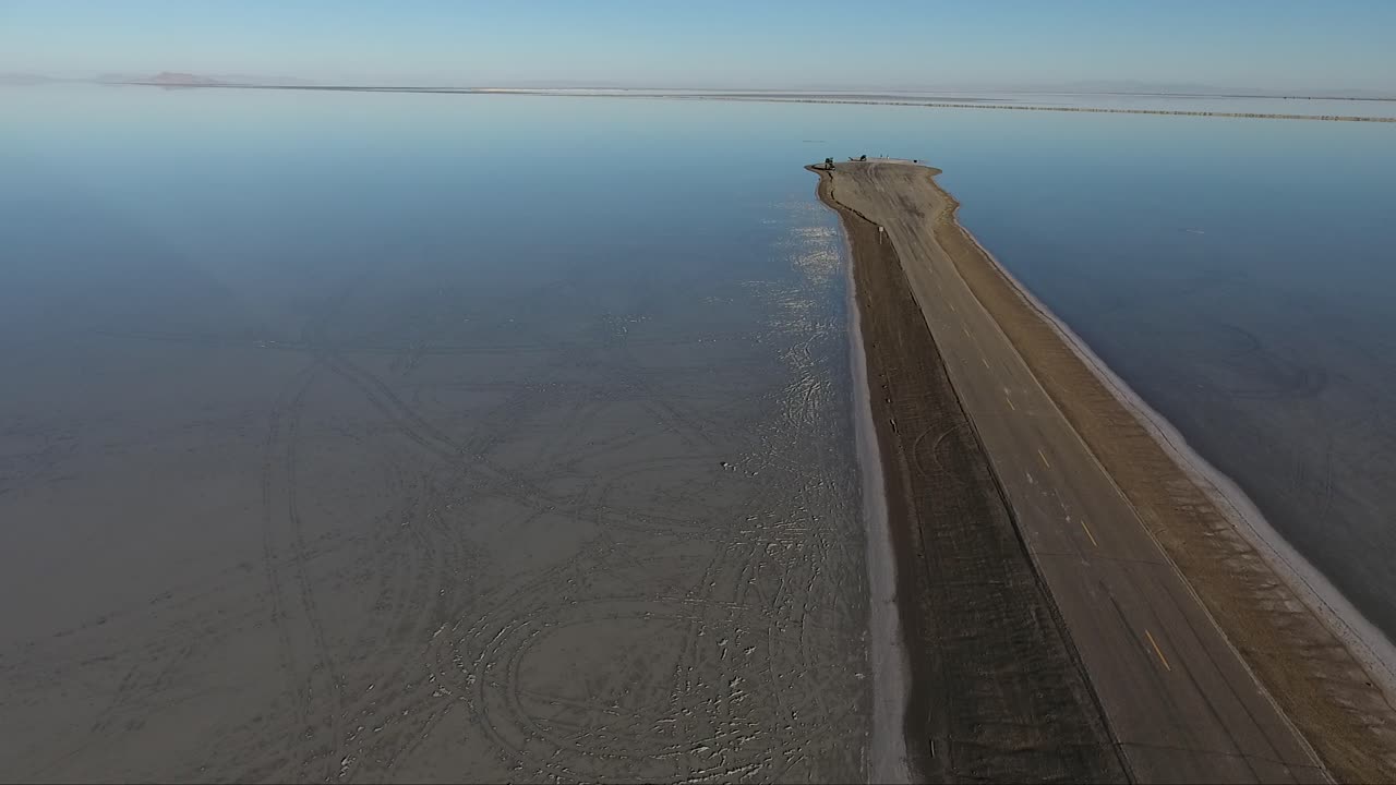 un dron que vuela sobre las salinas de bonneville muestra la calzada de las salinas que divide la salina inundada