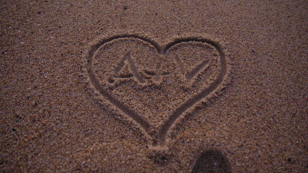 Hand Drawn Heart On Sand With Initials. high angle shot