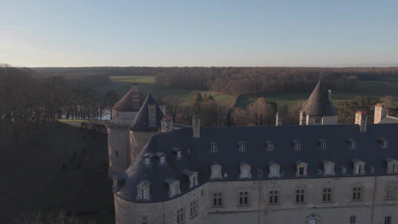 Une vue aérienne montre un petit château à tourelles avec un toit conique, situé près d'un méandre de la Loire