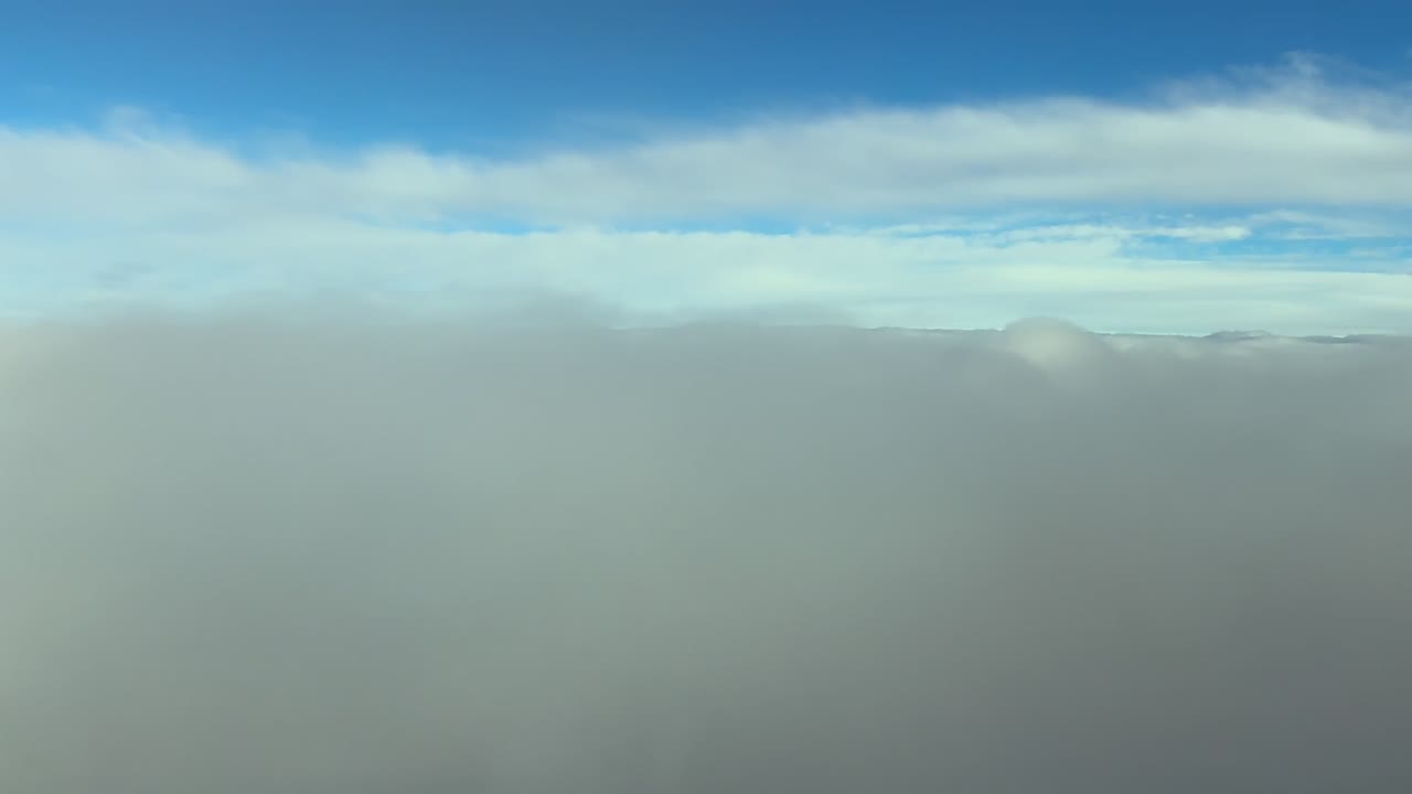 Vista de la cabina del piloto mientras desciende por una interminable capa de nubes estratos bajo un cielo azul