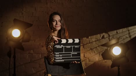 woman holding clapperboard in movie studio