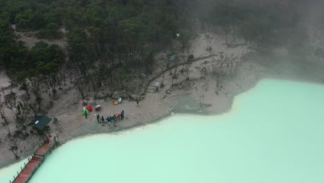 tourists on edge of extreme sulfur lake kawah putih in bandung indonesia, aerial