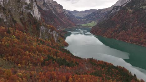 autumn colors surround klöntalersee with mountain cliffs in glarus, switzerland