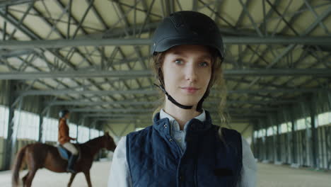 portrait of a young equestrian woman in an indoor riding arena