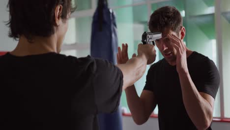 two caucasian men learning self defense from trainer in gym