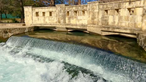 Agua-En-Movimiento-Rápido-Sobre-Un-Vertedero-Con-El-Reflejo-Del-Sol-Del-Agua-Blanca-Que-Crea