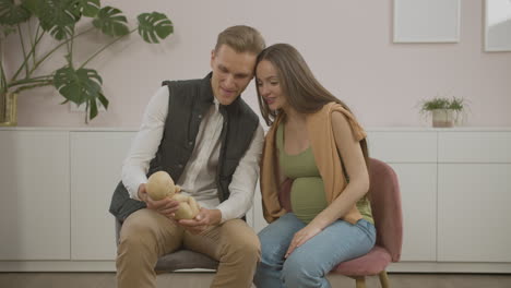 pregnant couple holding toy baby