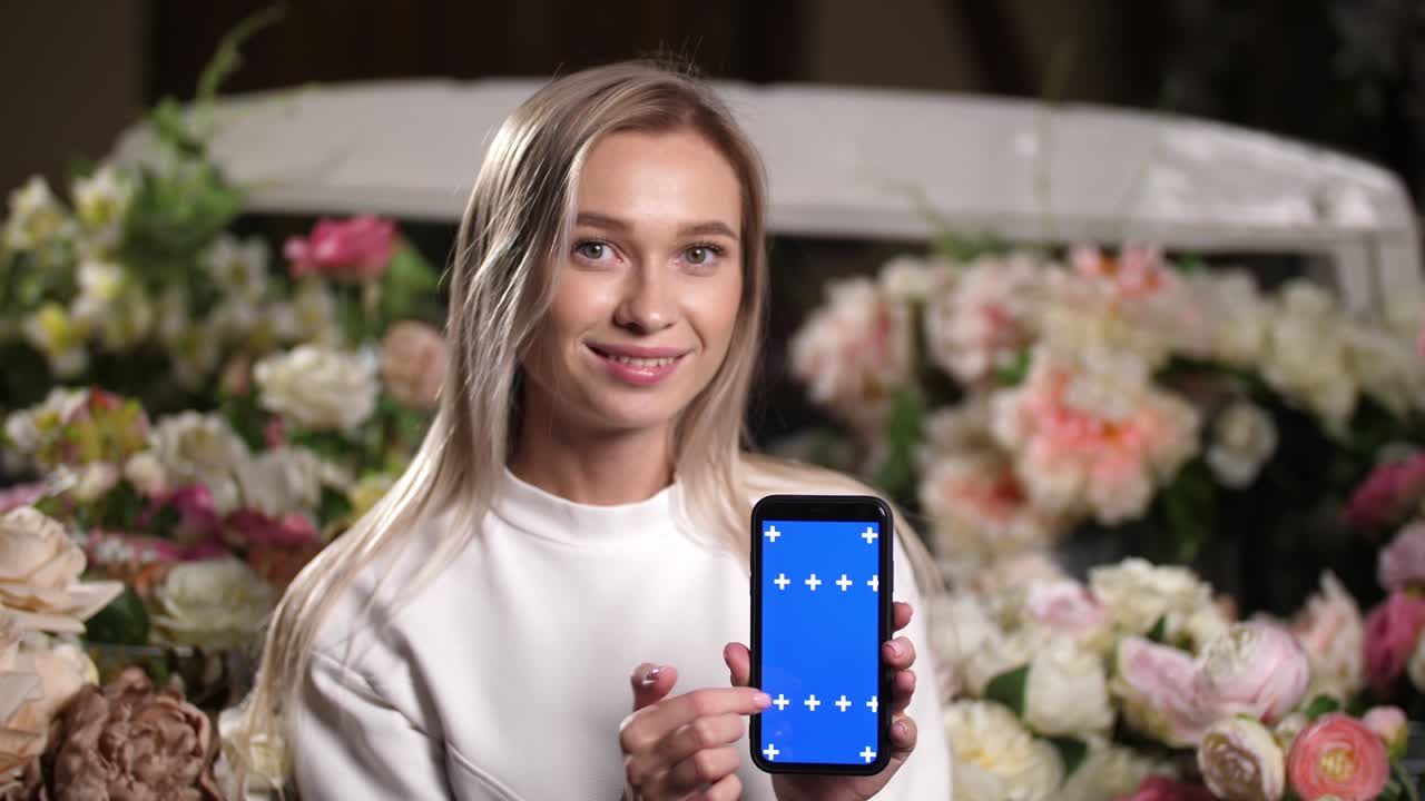 Donna sorridente tiene il telefono tra le mani, scorrendo e facendo scorrere lo schermo blu chroma key