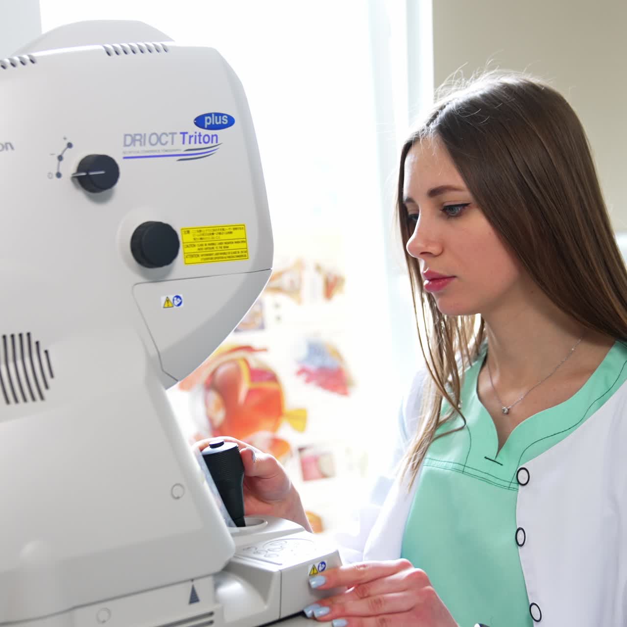 Beautiful young female doctor uses advanced technical equipment . Specialist moves the lever arm of device and looks at the screen