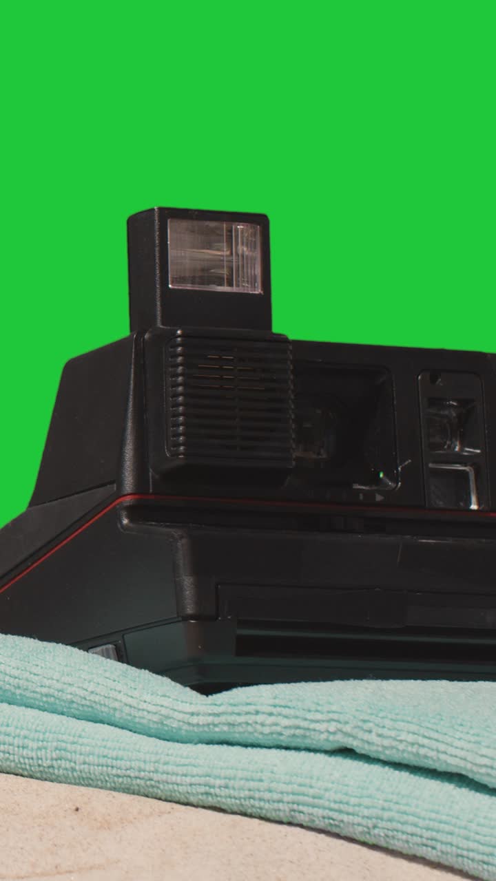 вертикальное видео летнего отдыха концепция человека, кладящего мгновенную камеру пляжное полотенце на песок против зеленого экрана