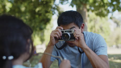 joven padre asiático fotografiando a su pequeña hija en el parque