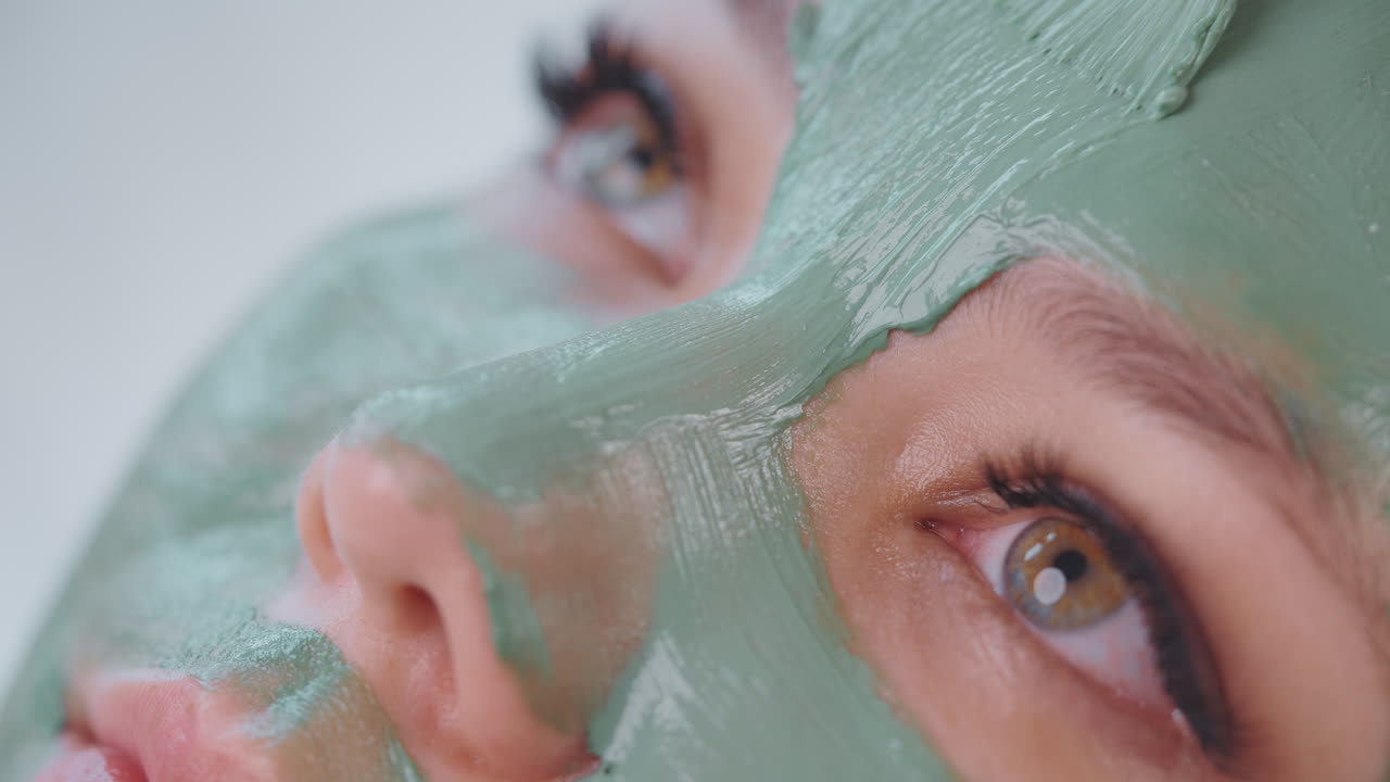 초록색 점토 얼굴 마스크를 입은 여자