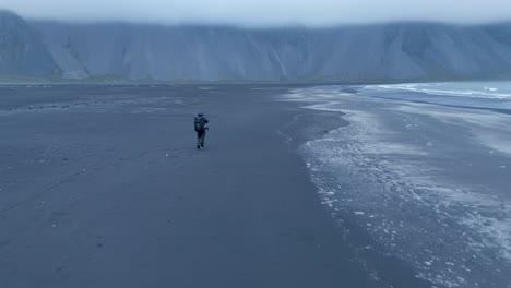 drone vuela sobre hombre solitario caminando en stokksnes