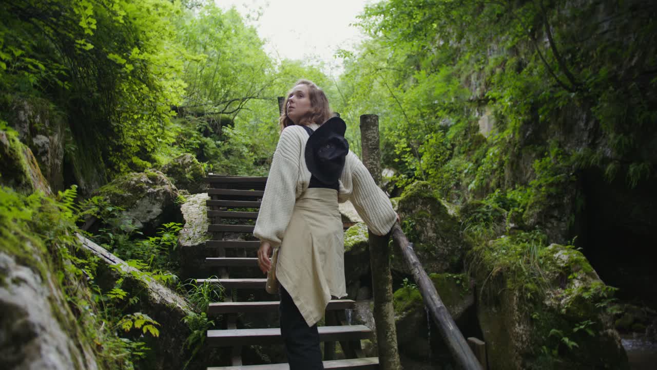 una mujer caminando a través de un exuberante cañón forestal.