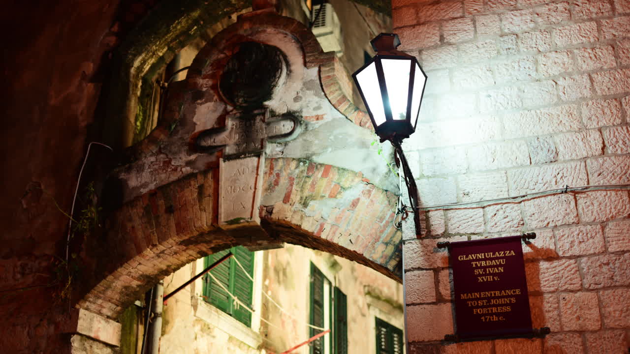 Stone archway and antique street lamp illuminating the entrance to St. John's Fortress. Kotor Old Town, Montenegro