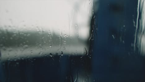 Close-up-of-rain-falling-on-a-the-window-of-a-boat-on-a-lake