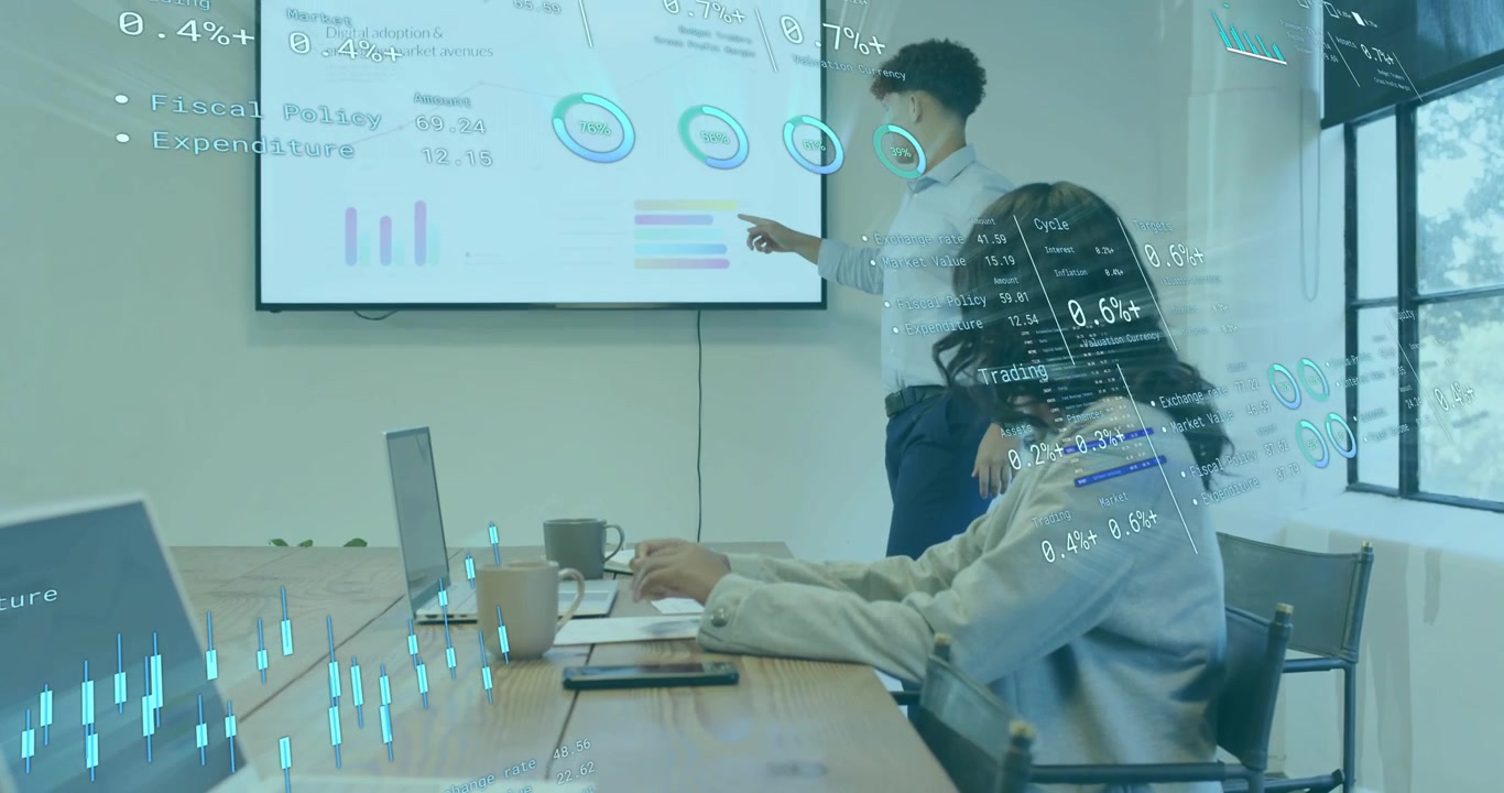 After reviewing documents, man standing presenting charts in business meeting with woman typing