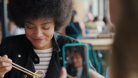 Joven-Afroamericana-Comiendo-Mariscos-En-Un-Restaurante-Mostrando-A-Su-Mejor-Amiga-Usando-Un-Teléfono-Inteligente-Tomando-Fotos-De-Amigos-De-Comida-Extraña-Divirtiéndose-Compartiendo-El-Fin-De-Semana-Juntos-En-Las-Redes-Sociales-4k