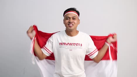Young Asian man celebrate Indonesian independence day on 17 August by holding the Indonesian flag isolated over white background