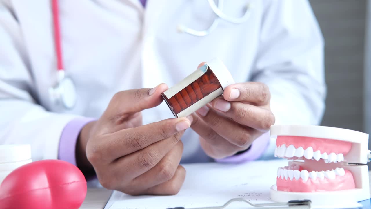 médico sosteniendo un recipiente de medicina y dientes modelo