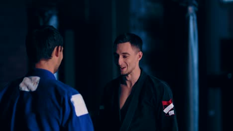 los hombres judokas se miran y se ríen. momento gracioso para los luchadores. movimiento circular de la cámara. vista de retrato.