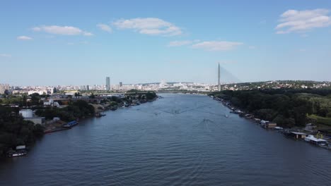 a wide river flows gracefully through a bustling cityscape, flanked by buildings, trees, and various urban structures. boats and small docks line the riverbanks