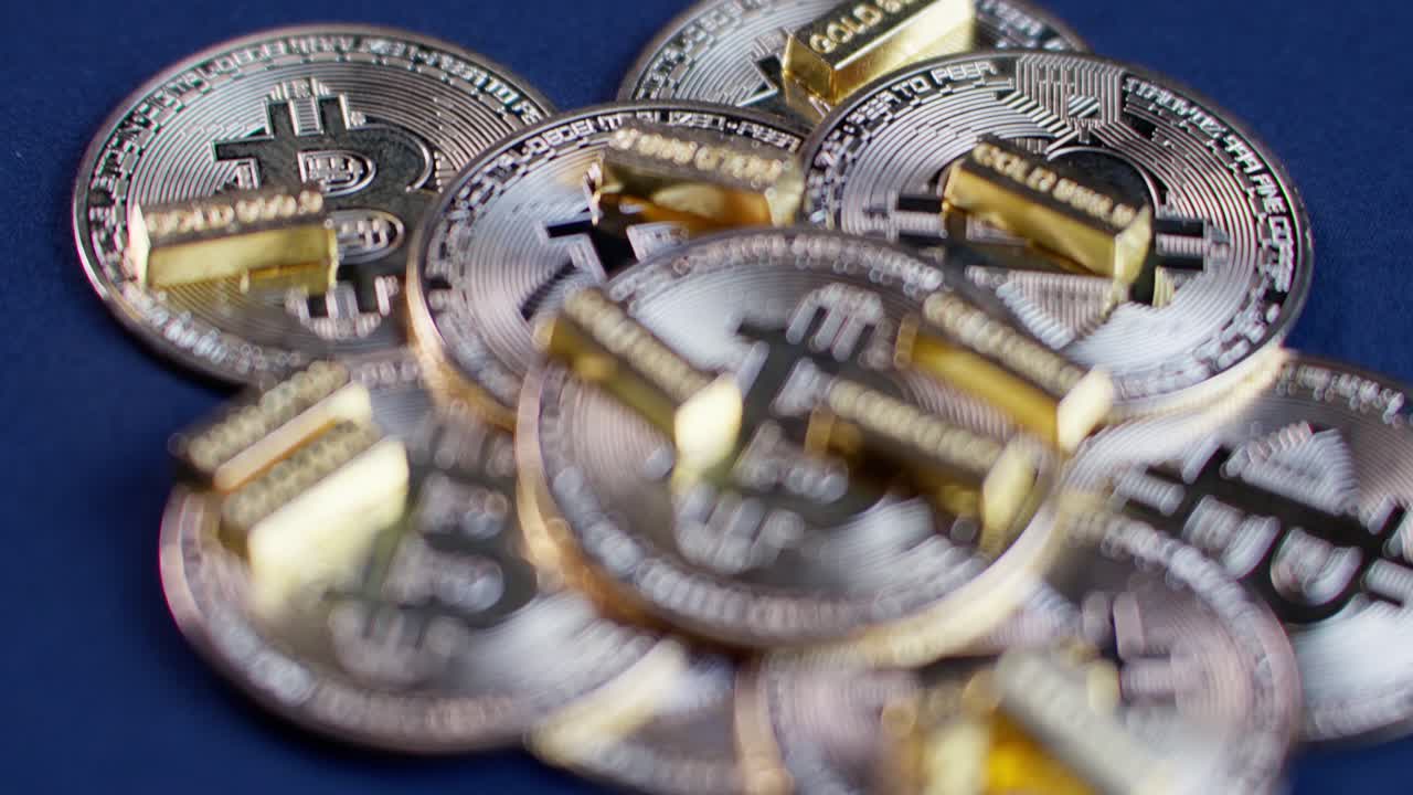 Handheld closeup of Bitcoin coins and gold bars, starting blurred and slowly coming into focus with slight camera movement