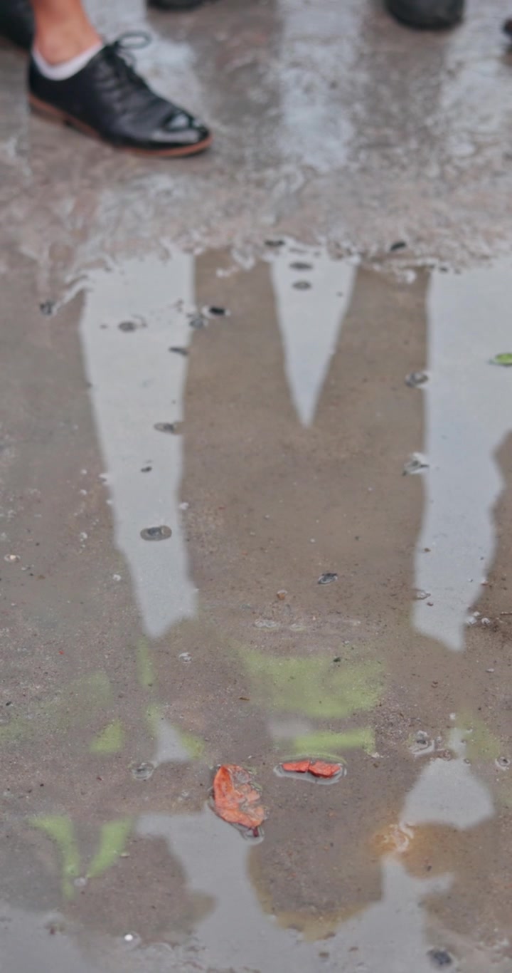 Refleksjon av mennesker som står i en sølepytt på en regnværsdag