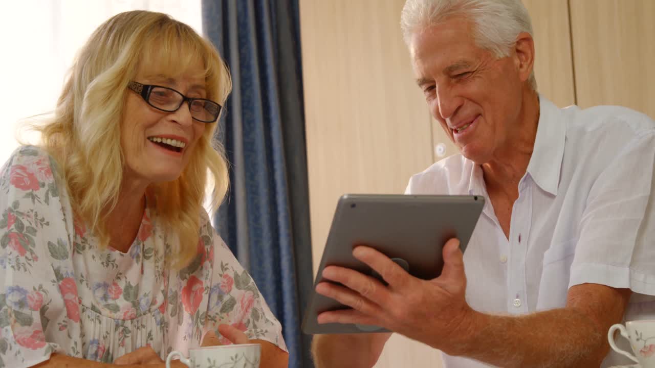 Coppia anziana felice che guarda un tablet