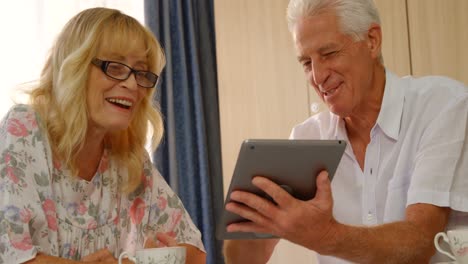 una pareja de adultos felices mirando una tableta digital.
