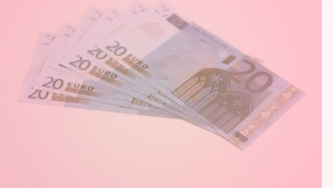 animatie van een close-up van eurobankbiljetten die op een roze achtergrond vallen.