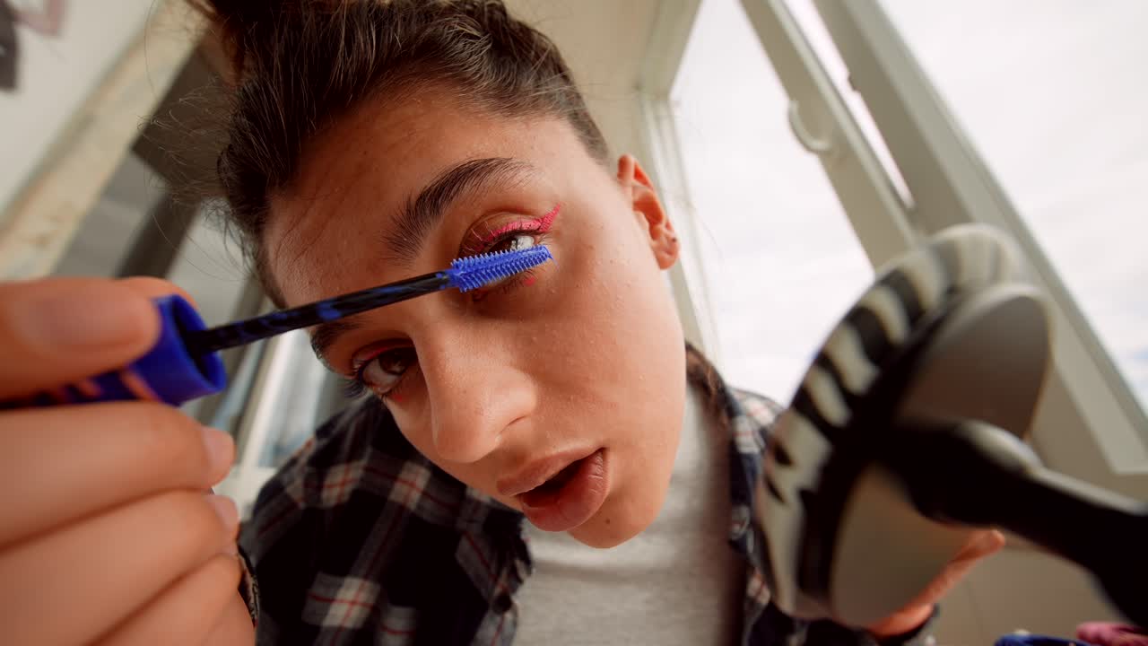 Young Woman Applying Mascara with Pink Eyeliner in Close-up