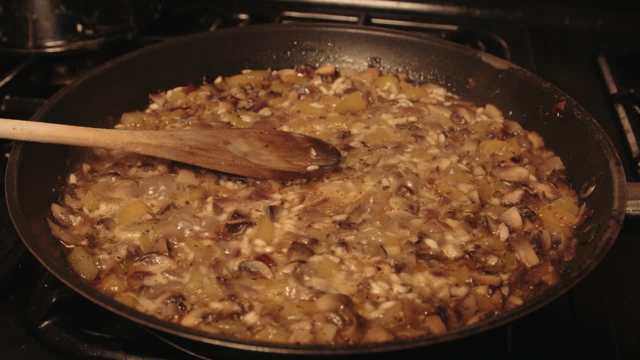 이탈리아의 버섯 리소토는 나무 ?? 가락으로  ⁇ 김판에서 요리하고 증기합니다.