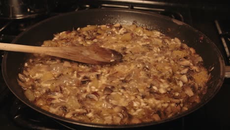 italian mushroom risotto cooking and steaming in frying pan with wooden spoon