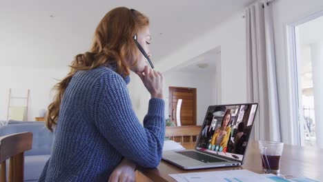 mujer caucásica con auriculares de teléfono haciendo una videollamada con una colega en una computadora portátil en casa